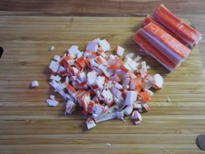 Крабовые палочки мелко порезать и добавить в салатницу