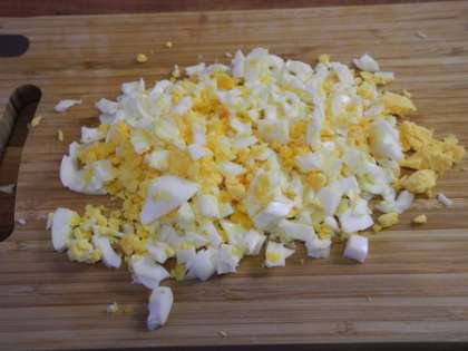 Отварные яйца почистить, мелко порезать и добавить в салатницу