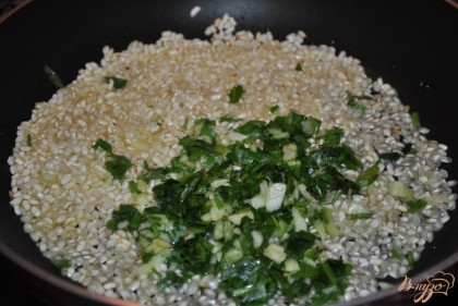 Добавить чеснок с петрушкой к рису и немного обжарить, помешивая.