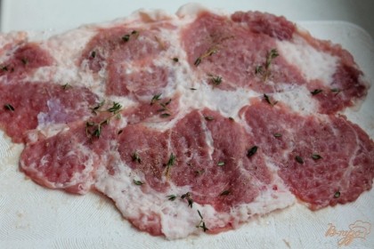 Отбитые куски мяса посыпаем солью, черным молотым перцем и листочками душицы.