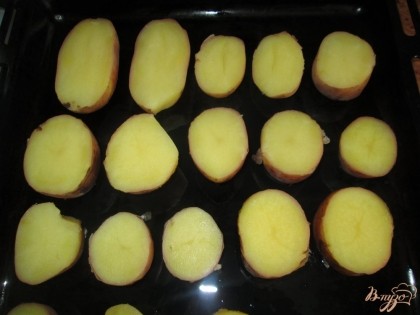 Отваренный картофель, не очищая, разрезаем на половинки и выкладываем на смазанный маслом противень.