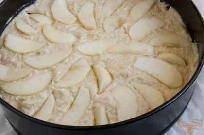 Выложить тесто в форму, застеленную пергаментной бумагой, разровнять. Сверху выложить ломтики оставшихся яблок (без кожуры и сердцевины), слегка вдавить их в тесто. Выпекать пирог 60 минут при 180 градусах. Ставить его нужно в разогретую духовку.