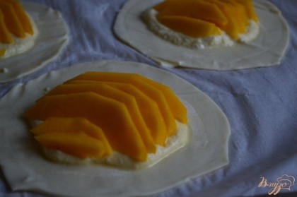 Из теста вырезать большие круги. Разложить крем и дольки манго.