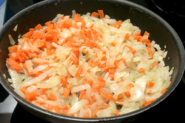 Разогреть в сковороде масло растительное и сливочное, закинуть туда лук и морковь — обжарить до легкого золотого цвета.
