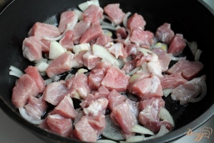 На сковородку наливаем подсолнечное масло и ставим на огонь. Свинину нарезаем кусочками и кладем на разогретую сковородку. К мясу добавляем нарезанный репчатый лук.