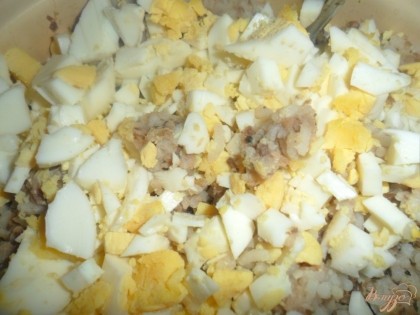 Яйца отварить, почистить и мелко порезать, так же мелко порезать лук.Смешать рис, консервы. лук и яйца. посолить заправить майонезом.