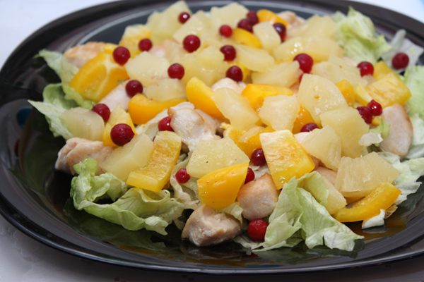 На большую тарелку выкладываем слоями листья салата, курицу, ананас и перец, поливаем заправкой и украшаем ягодами брусники.