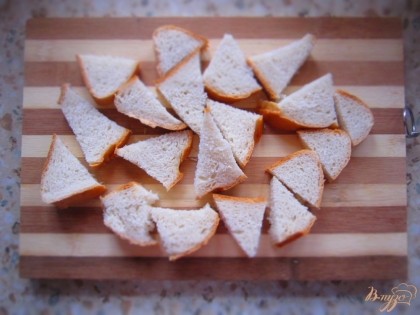 Пока крем остывает. Нарежьте на произвольные кусочки хлеб, выложите в форму для запекания. Яблоко нарежьте кубиком и выложите сверху на хлеб. Также добавьте изюм.