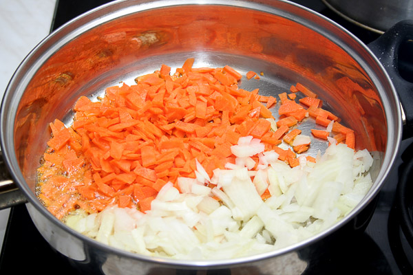 Разогреть в глубокой сковороде (или сотейнике) масло, закинуть лук и морковь. Обжарить до легкого золотистого цвета.