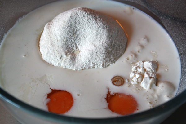 В миску просеять муку, добавить яйца, соль, сахар и половину молока.