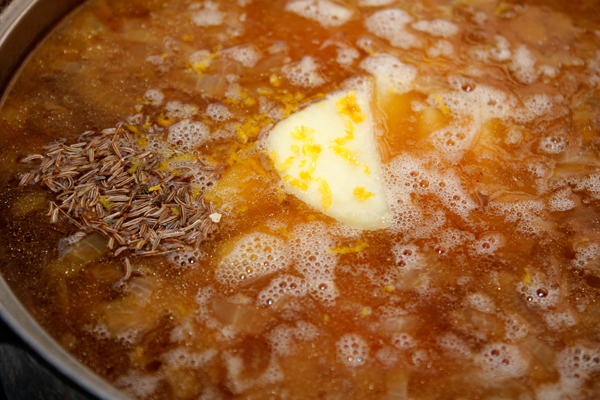 Добавить в суп тмин, натертую лимонную цедру и варить, пока мясо и картофель не станут мягкими.