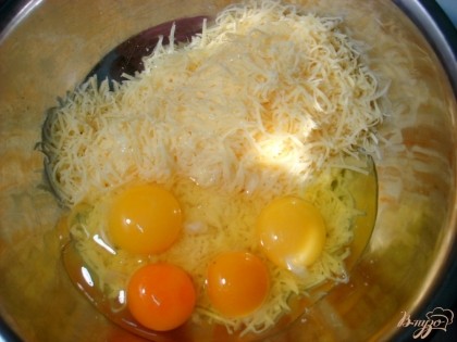 Противень застелить бумагой для выпечки.Сыр натереть на мелкой тёрке, добавить яйца, тщательно перемешать.