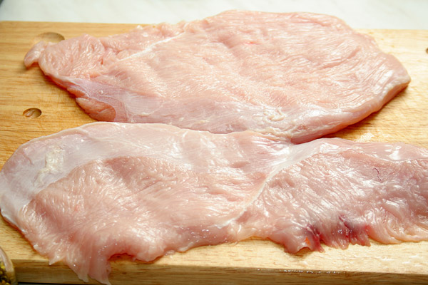 Вымыть филе грудки и порезать большими кусками толщиной 2 см, накрыть пищевой пленкой, слегка отбить.
