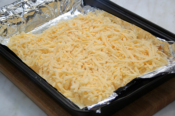 Потереть сыр и выложить поверх ананасов. Поставить в духовку на 25 минут. <p>  Если у Вас есть в духовке функция верхнего гриля, то последние 3 минуты запекайте им.