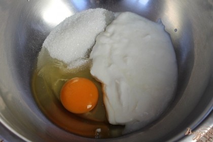 В миску насыпаем сахар, натуральный йогурт и добавляем яйцо. Ингредиенты перемешиваем.