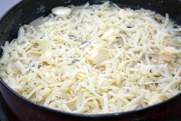 На грибную начинку положить оставшуюся картошку, посыпать тертым сыром и положить небольшие кусочки масла.