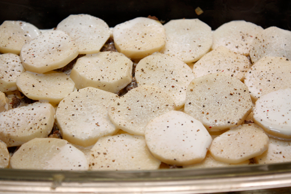 Снова накрыть его слоем картофеля, полить сливками, посолить и поперчить.  Чередовать слои так, чтобы сверху оказался картофель, политый сливками.