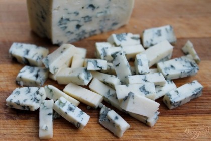 Голубой сыр режем небольшими кусочками и кладем на листья.