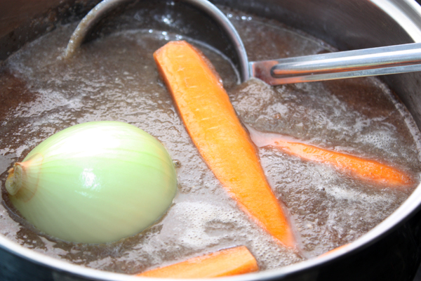 В кастрюлю с грибным пюре нужно положить луковицу и разрезанную вдоль морковь и поставить тушить на небольшом огне под крышкой около получаса.  Затем удалить лук и морковь.