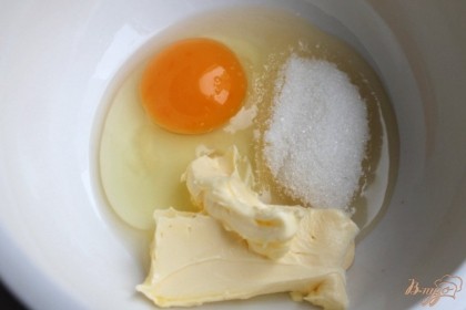 В пиалу насыпаем сахар, вбиваем яйцо и кладем мягкое сливочное масло. Все ингредиенты перемешиваем.