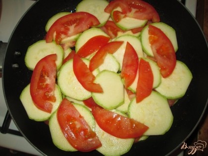 Уложить в сковороду, смазанную растительным маслом и добавить порезанный полукольцами свежий помидор.