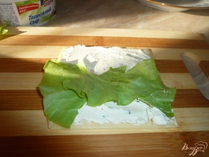 Затем кладем кусочек листа салата. Лучше салат класть так, чтобы он немного "выглядывал" сверху сыра. Также на сыр можно положить кусочек свежего огурчика, оливку или маслину - по вашему вкусу и желанию.