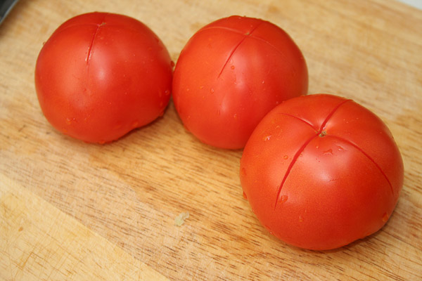 Сделать неглубокий разрез на помидорах и опустить их в кипяток на 2-3 минуты. Затем очистить их от кожуры и натереть на мелкой терке.