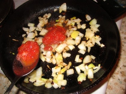В той же сковороде, где жарилось мясо. Положите нарезанный лук и обжарьте до золотистого оттенка, добавьте томатную пасту и перемешайте.