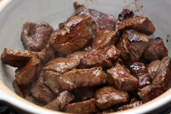 Обжаренное мясо выложить в кастрюлю или глубокую сковороду с толстыми стенками, немного посолить.