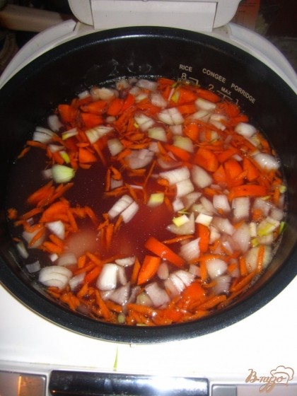 В мультиварку положите куриные голени и морковь с луком. Тушите примерно 30 минут.