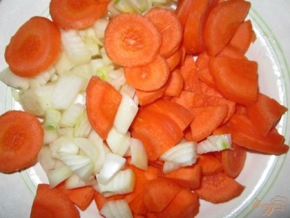 Очистить от кожицы, помыть и нарезать кружочками морковь.  Лук очистить от шелухи и мелко нарезать. И добавить в кастрюлю.