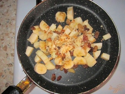  Яблоко и банан выложить  на сковороду, добавить промытый, обсушенный изюм,измельченные орехи, мед. Перемешать и готовить около 1 минуты. После чего влить немного воды и тушить до мягкости яблок.