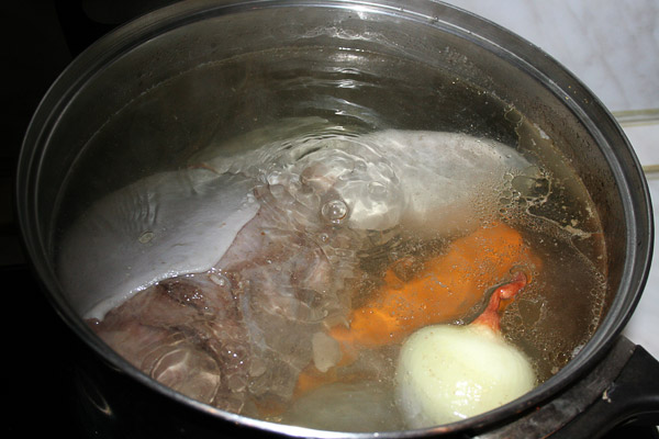 Зачистить язык под водой, поскоблив его ножом. Положить язык в кастрюлю и налить холодной воды. Поставить на плиту и вскипятить, как и при варке обычного мяса поднимется пена, которую обязательно нужно снять. Уменьшить огонь, полуприкрыть крышкой и варить 1 час, после чего закинуть в очищенные овощи и коренья: лук, морковь, четверть корня сельдерея, корень петрушки.<p>  Продолжать варить на медленном огне еще 45 минут, после чего добавить соль, лавровый лист, перец горошком. Варить еще 15−20 минут, затем проверить готовность вилкой, при необходимости варить еще 15−20 минут. 