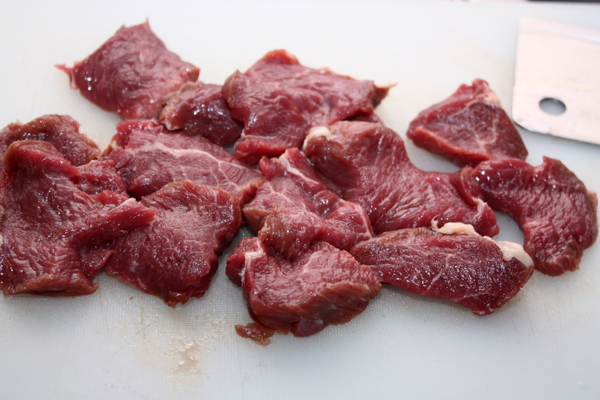 Мясо очистить от жил и порезать поперек волокон на плоские куски толщиной около 1,5 см. Чтобы мясо было мягче, его можно отбить.  Теперь каждый кусок разрезать на небольшие кусочки.