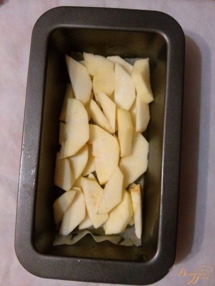Яблоки очистите от кожуры, нарежьте дольками. Форму для кексов, застелите бумагой для выпечки, смажьте растительным маслом и покладите яблоки.