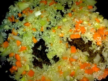 Морковь и лук обжарить несколько минут. Затем добавить к овощам рис и чеснок. Посолить и поперчить. Долить воды и потушить 5 минут.