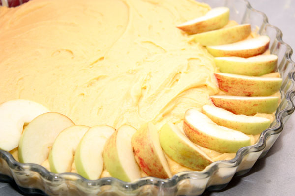 В смазанную сливочным маслом форму выкладываем тесто и слегка разравниваем.   Сверху по кругу укладываем дольки яблок слегка внахлест.
