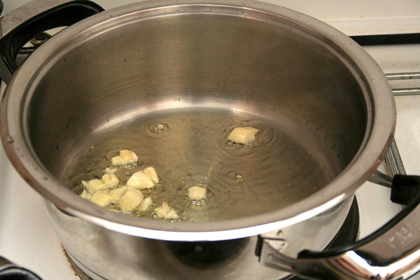 Разогреть масло в большой сковороде или широкой кастрюле, добавить чеснок и слегка его обжарить до мягкости.