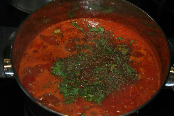 Нарезать листья зелени, которая осталась с предыдущего этапа, всыпать в кастрюлю, туда же добавить и специи. Варить еще 5 минут, после чего, измельчить томаты блендером.