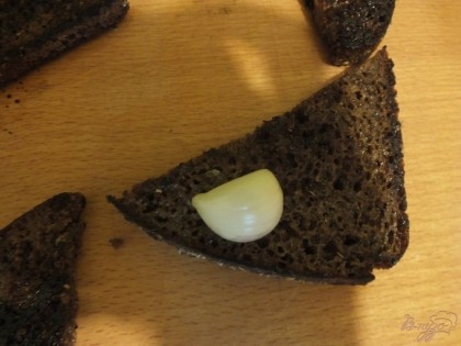 Дальше долькой чеснока хорошо с одной стороны натрите хлеб. В среднем уходит 0.5 - 1 зубок на 1 гренку.