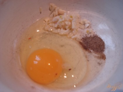 Чеснок очищаем и измельчаем. В миску вбиваем яйцо, солим и перчим по вкусу, добавляем измельченный чеснок,
