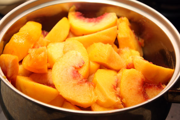 Персики нужно вымыть, очистить от кожицы и удалить косточки. Нарезать небольшими дольками и положить в кастрюлю.