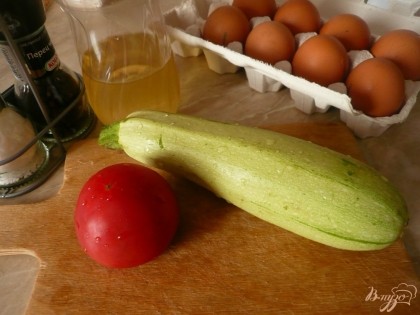 Подготовим все ингредиенты для яичницы: небольшой молоденький кабачок, помидор, куриные яйца (с перепелиными тоже хорошо, вместо одного куриного берем пять перепелиных). Кроме того понадобится соль, черный молотый перец ну и растительное масло для жарки. Промываем кабачок, помидор, яйца. Кабачок зрелый, который уже надо чистить от кожуры и семян использовать не стоит, только молоденький.
