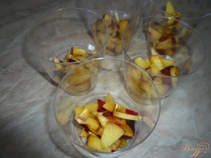 Распределяем нарезанные персики по порционным стаканчикам. В порционных стаканчиках удобнее подавать десерт, но можно использовать и одну большую форму.