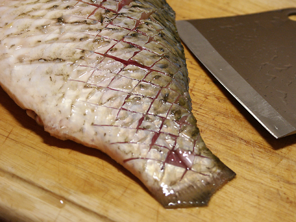 Слегка посолим рыбу. Имейте в виду, что надрезанная таким образом рыба, требует гораздо меньше соли, чем рыба, зажариваемая целиком и без надрезов. Так что не пересолите, пожалуйста.<p>  В глубокой сковороде, лучше с антипригарным покрытием или чугунной, разогрейте 300 мл растительного масла. Разогрейте сильно, чтобы над поверхностью появился легкий дымок. Можно просто пожарить карасей в этом масле, и получится очень вкусно, но я рекомендую добавить этому блюду азиатские нотки. Для этого, в масло нужно бросить слегка раздавленный зубчик чеснока и несколько ломтиков имбиря. Они отдадут свои пряные ароматы маслу, а масло передаст их рыбе. Получится восхитительно.<p>  Рыбу осторожно (брызгается!) кладем в масло и обжариваем по 5 минут с каждой стороны. Обжаривать надо каждую рыбку по отдельности, тогда масло будет оставаться достаточно горячим.  