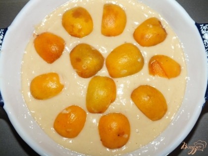 Получившееся тесто выложите в смазанную форму для выпечки. На тесто положите абрикосы, порезанные на половинки.