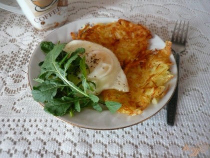 Готово! На порционные тарелки выкладываем по две картофельных оладьи, сверху на них жареное яйцо. Добавляем по паре веточек руколы. Завтрак готов, приятного аппетита!