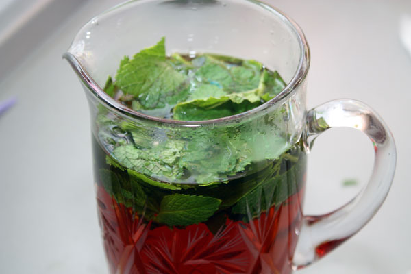 Горячий чай процеживаем и добавляем туда сахар и листья мяты. 