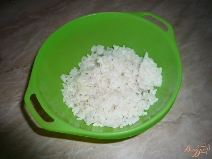 Первым делом отвариваем до готовности рис и яйцо (вкрутую). Если используется обычный рис, не в пакетиках, то его предварительно промываем под проточной водой. Куриные яйца также не забываем предварительно вымыть. В процессе варки рис подсаливаем (соль добавляем в воду для риса, когда она закипит, после этого закладываем рис). Готовый рис откидываем на дуршлаг и даем обтечь воде. После этого перекладываем рис в глубокую плошку.