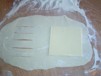 Каждый кусок теста раскатываем в тонкие прямоугольные пласты, на один край кладем сыр, а второй край надрезаем, как показано на фото.